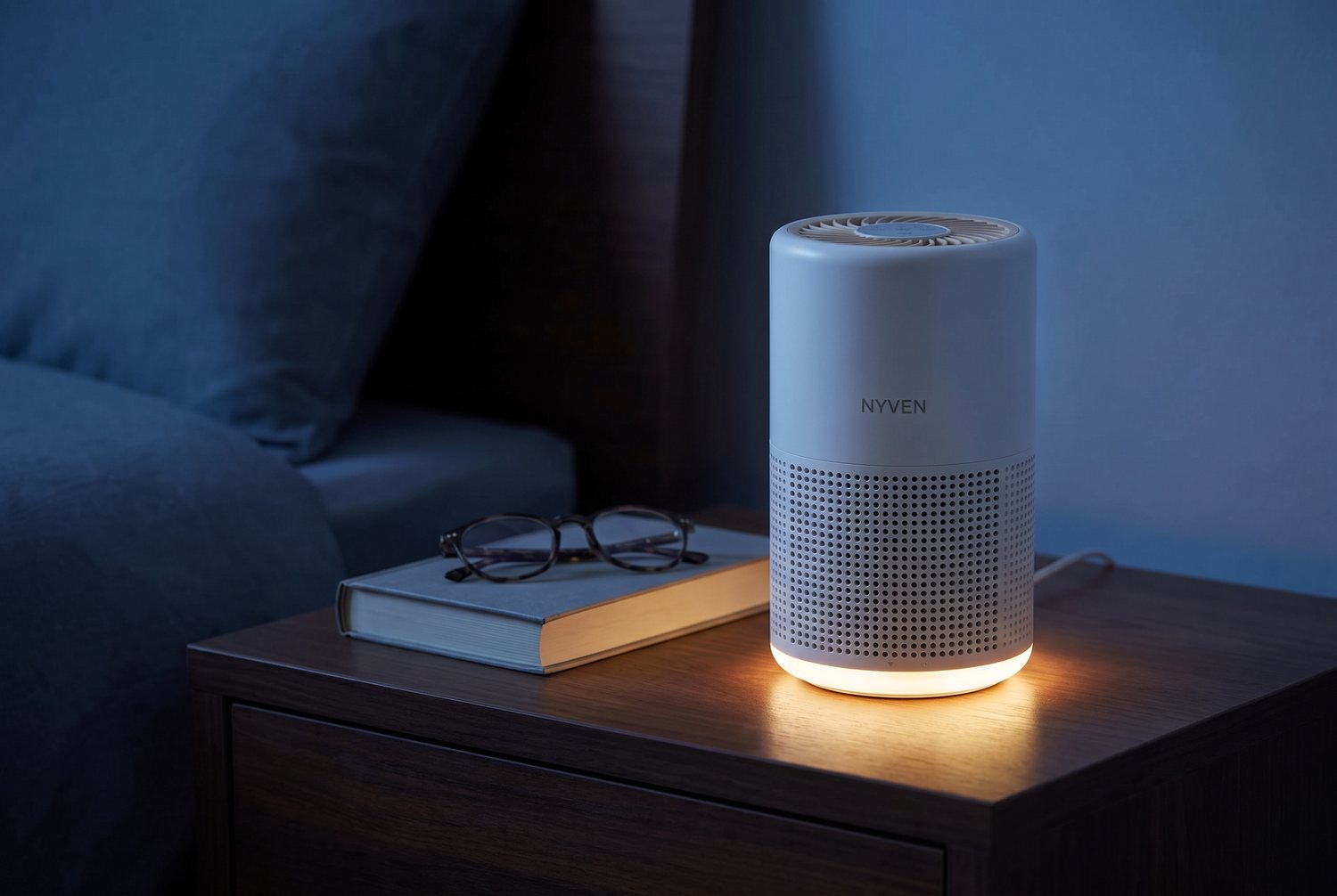 The YOMA A2 air purifier on a wooden nightstand at night with its warm night light glowing.
